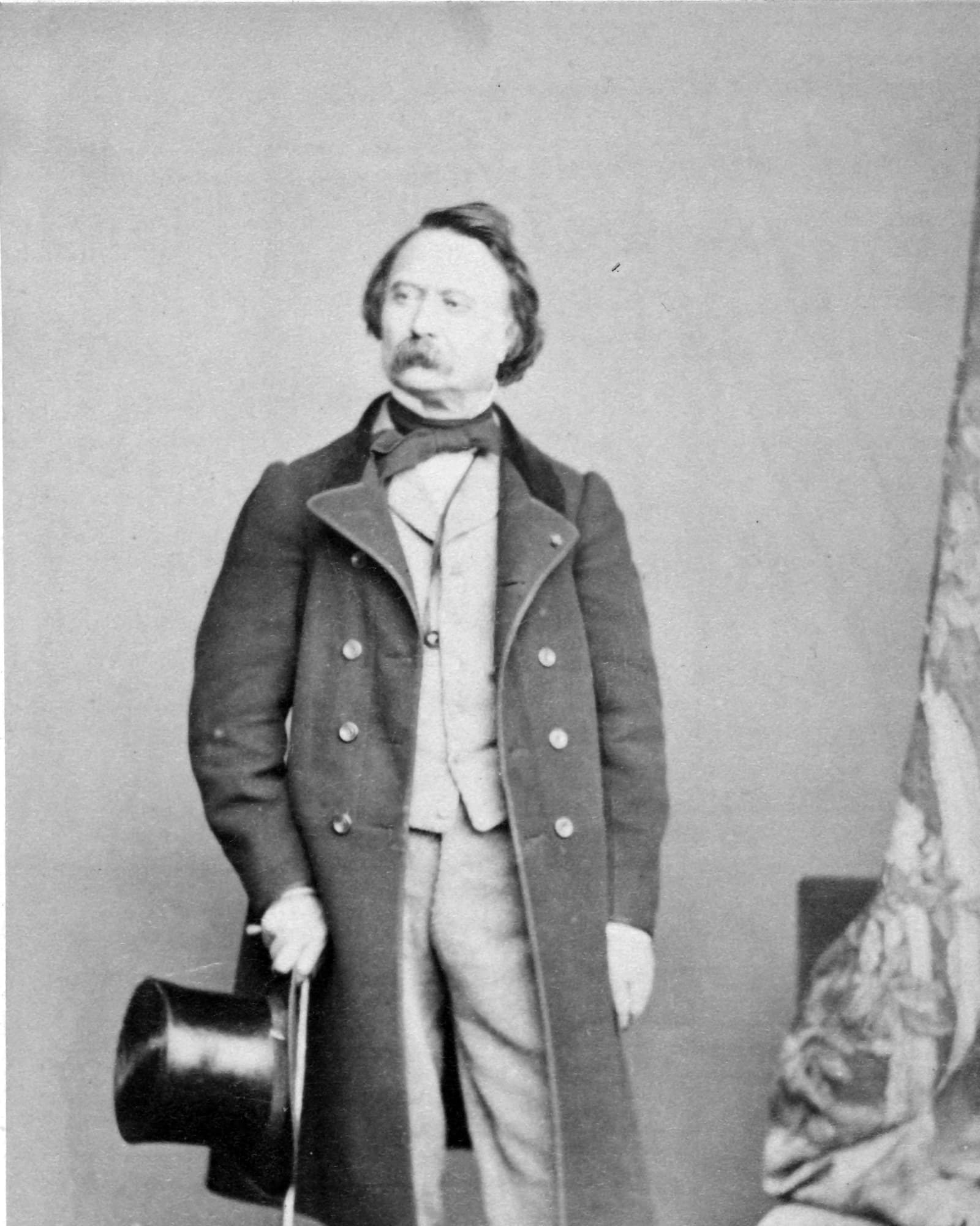 Portrait en pied de l’architecte Henri Labrouste, en redingote, chapeau haut-de-forme et canne à la main.